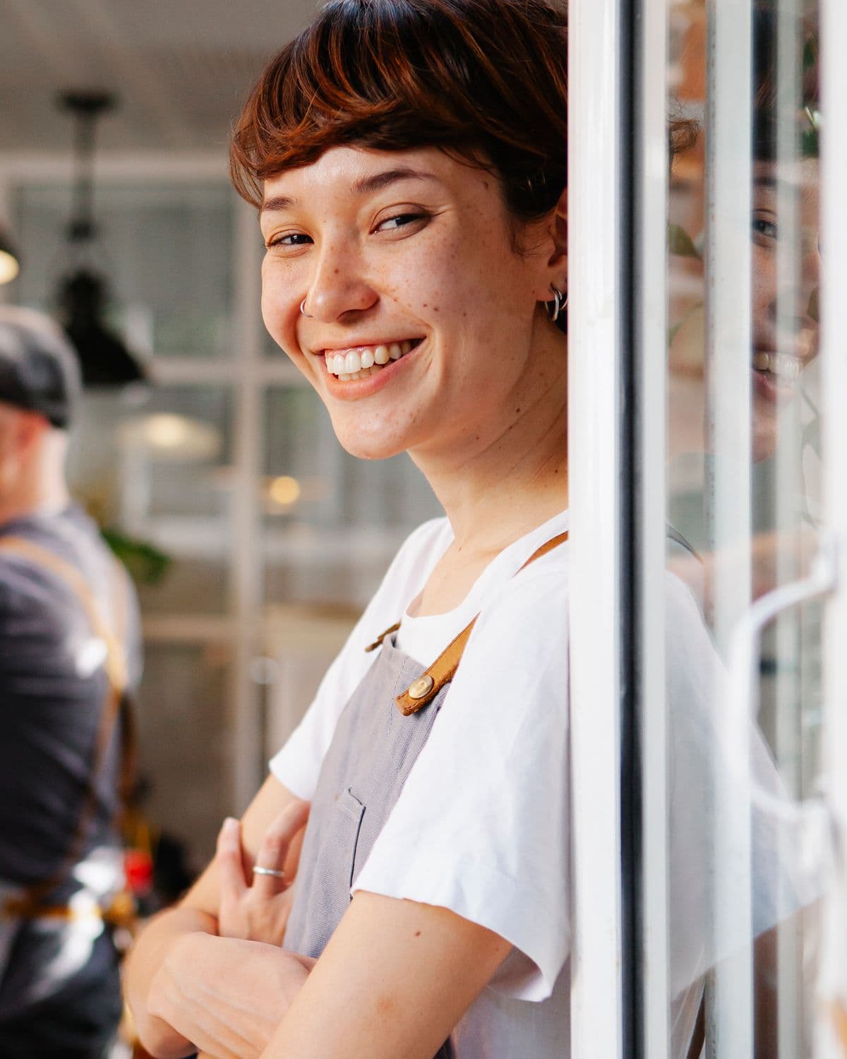 A small-business owner in an apron, smiling to camera in her shop